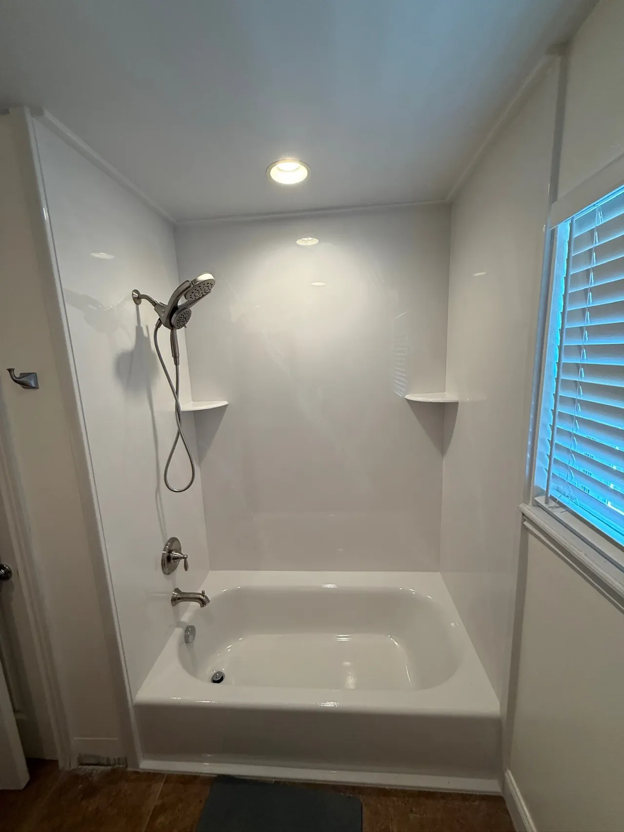 White tub and shower combo with dual showerheads and chrome fixtures