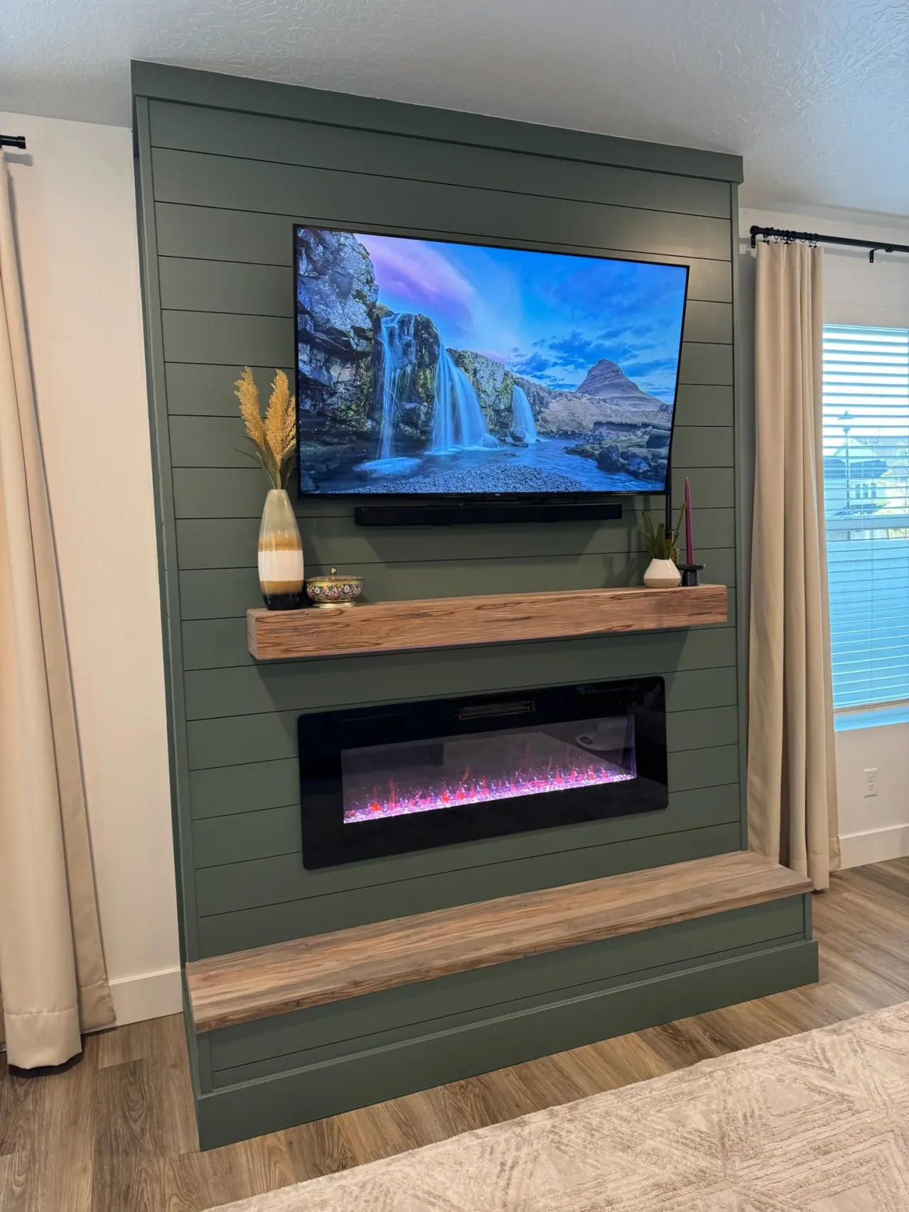 Green shiplap fireplace with built-in bench, wood mantel, and wall-mounted TV