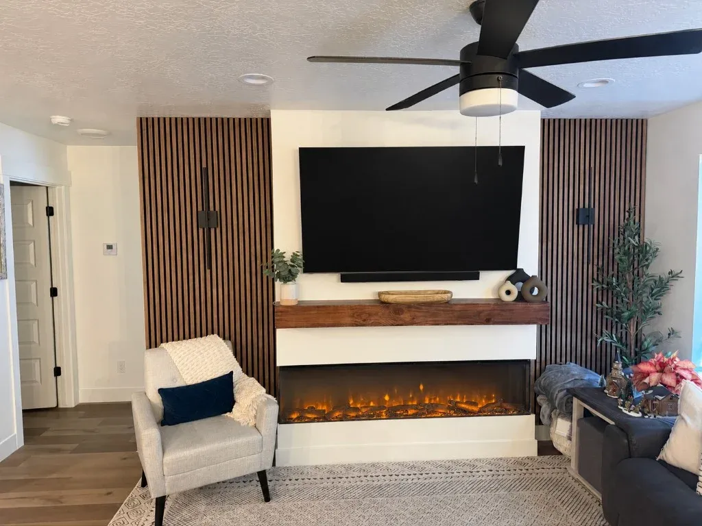 Built-in linear electric fireplace with wood mantel and vertical wood slat accent wall in a Utah home
