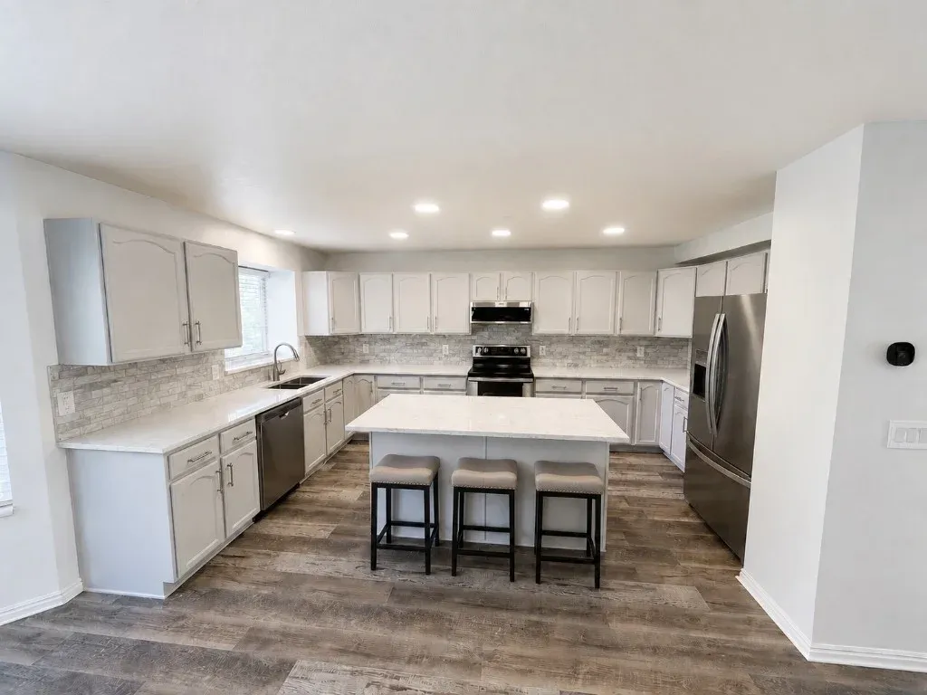 Kitchen remodel with white cabinets, quartz countertops, island seating, and tiled backsplash in a Utah home